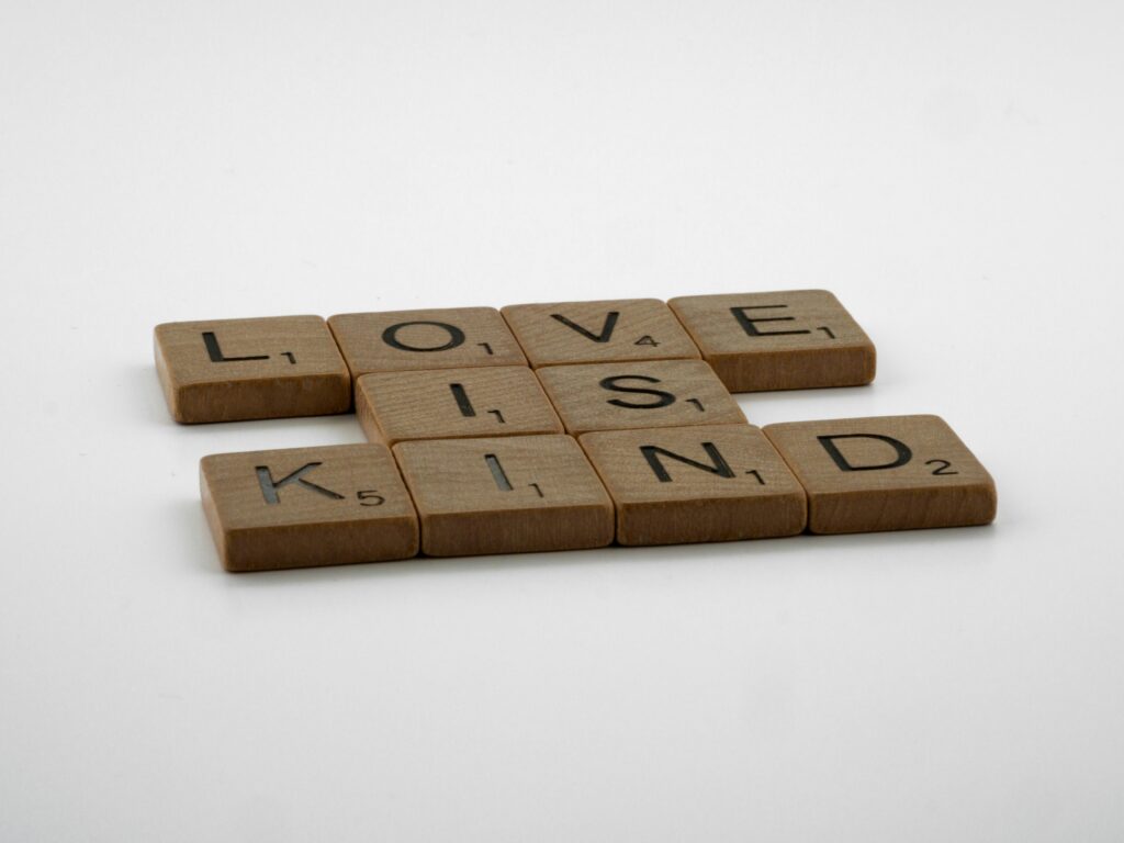 Kindle Ads – jak skutecznie promować książki na Amazon? Kindle Ads – drewniane kostki z napisem love is kind jako symbol skutecznej reklamy książek i promocji ebooków na Amazon Kindle
