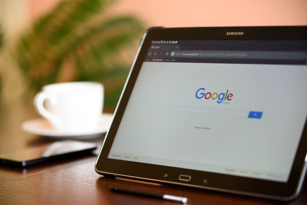 Jak pisać do Google? Skuteczna reklama w Google Ads krok po kroku Jak napisać do Google – tablet z otwartą wyszukiwarką Google na ekranie, symbol kontaktu z obsługą i wsparciem technicznym.