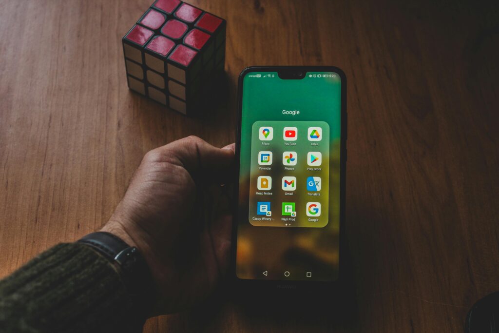 Smartfon z aplikacjami Google na ekranie – wizytówka Google Maps jako kluczowy element widoczności lokalnej firmy, pozycjonowania w mapach i pozyskiwania klientów online.
