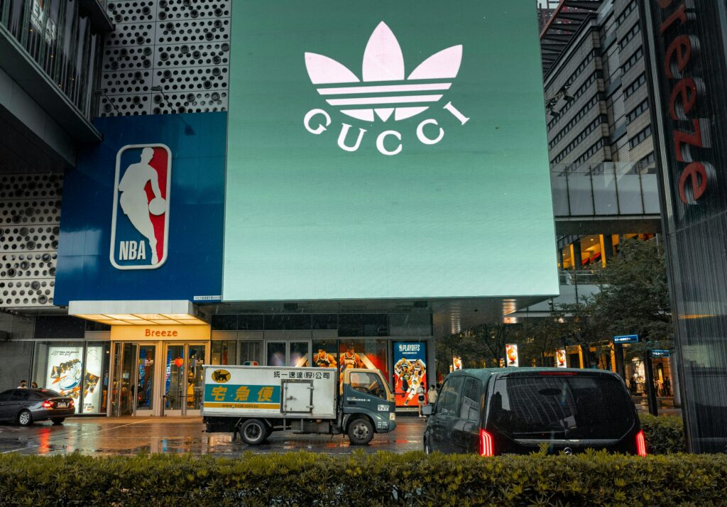 Duży ekran reklamowy z logo znanej marki przy wejściu do galerii handlowej w centrum miasta – skuteczna reklama i promocja w przestrzeni miejskiej przyciągająca uwagę klientów.
