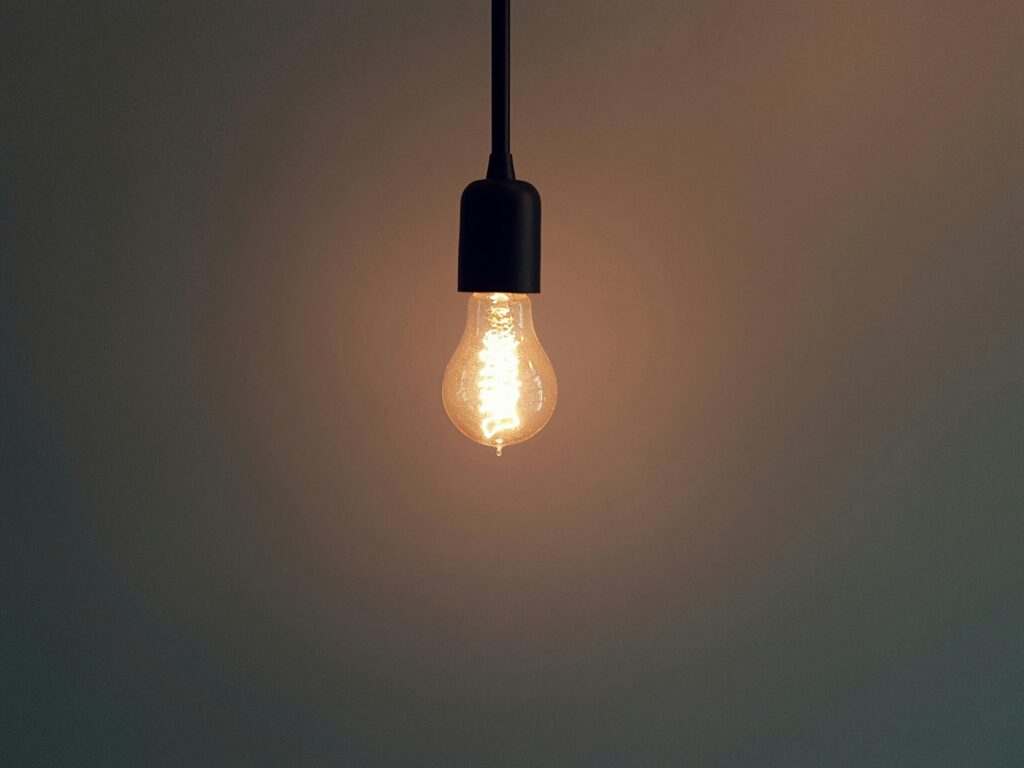 Świecąca żarówka na minimalistycznym tle – smarketing jako połączenie sprzedaży i marketingu generujące nowe pomysły, wzrost konwersji i skuteczną strategię rozwoju firmy.