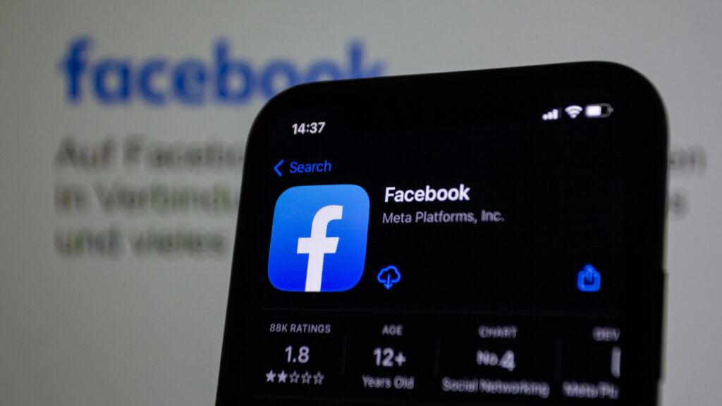 Kampanie reklamowe na Facebooku – jak tworzyć skuteczne oferty? Kampania reklamowa Facebook – aplikacja Facebook na ekranie smartfona, reklama w systemie Meta Ads.