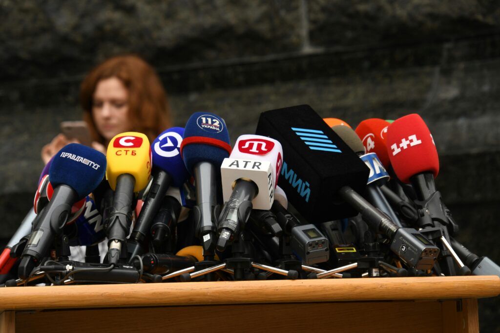 Owned media – czym są i jak budują silną markę? Owned media – zestaw mikrofonów podczas konferencji prasowej jako symbol własnych kanałów komunikacji marki, publikacji firmowych i budowania wizerunku w mediach.