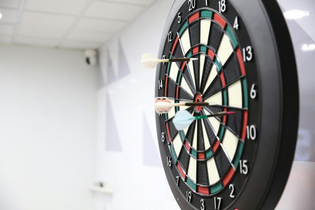 Retargeting marketing – jak odzyskać klientów i zwiększyć konwersję? Retargeting marketing – tarcza do darta z rzutkami w centrum symbolizująca precyzyjne docieranie do klientów i ponowne targetowanie reklam