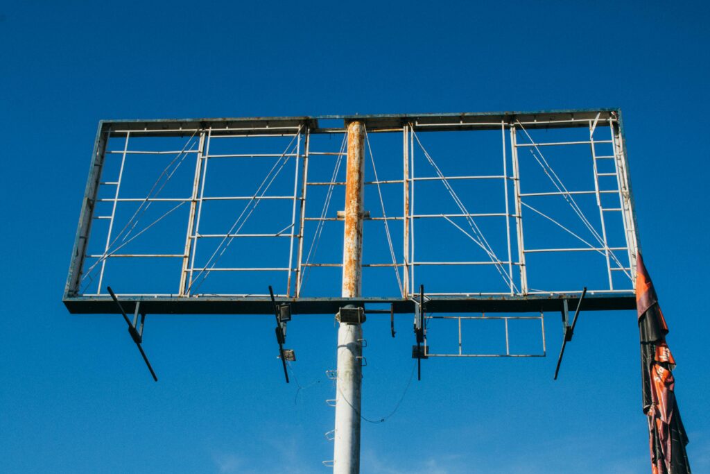 Outdoor marketing – jak skutecznie budować rozpoznawalność marki poza internetem? Outdoor marketing – konstrukcja billboardu reklamowego na tle nieba jako przykład reklamy zewnętrznej i promocji marki w przestrzeni publicznej