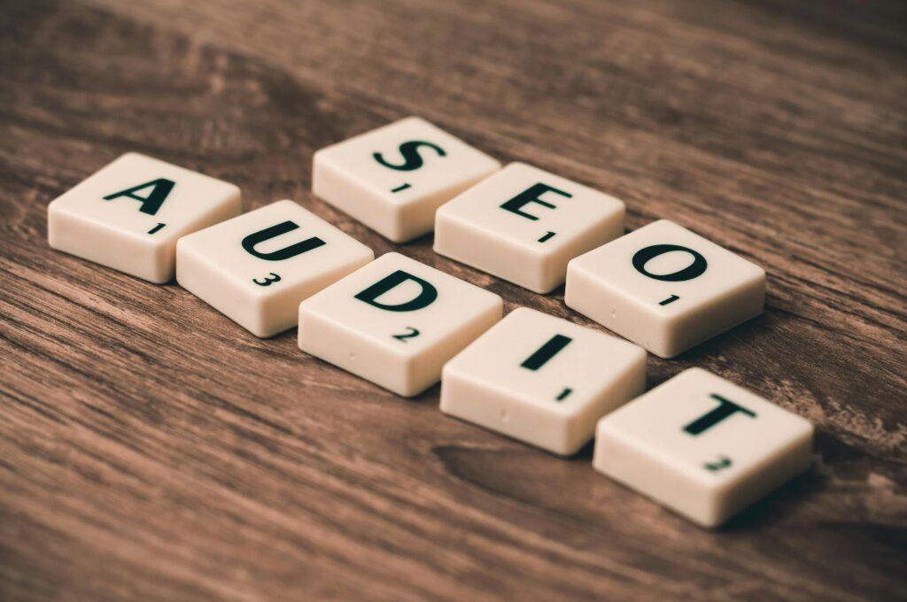 Copywriter SEO – kim jest, czym się zajmuje i dlaczego jest kluczowy dla widoczności w Google? Klocki z napisem „AUDIT SEO” na drewnianym tle – copywriter SEO co to, czyli specjalista tworzący treści zoptymalizowane pod wyszukiwarki, które zwiększają widoczność strony i ruch organiczny.