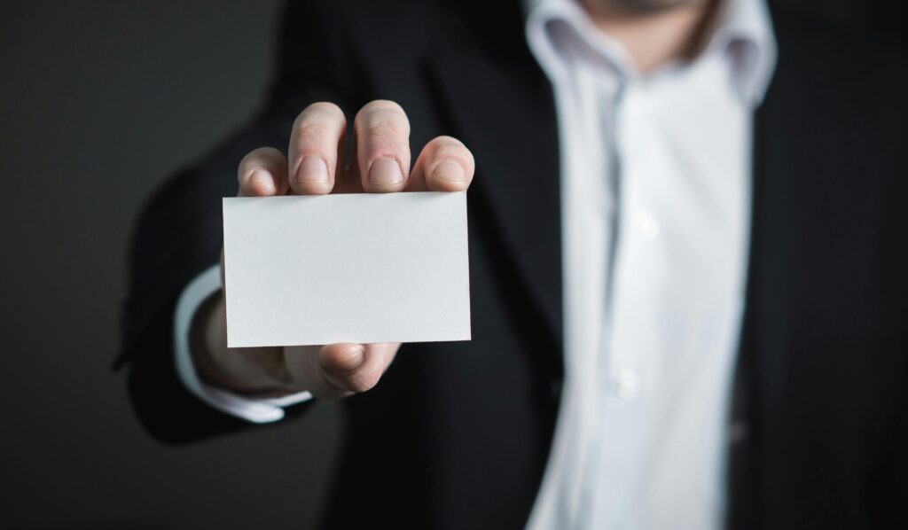 Remarketing – co to jest i jak remarketing manager zwiększa sprzedaż? Remarketing co to – biznesmen trzyma pustą wizytówkę symbolizującą ponowne dotarcie do klienta i strategię marketingową online.