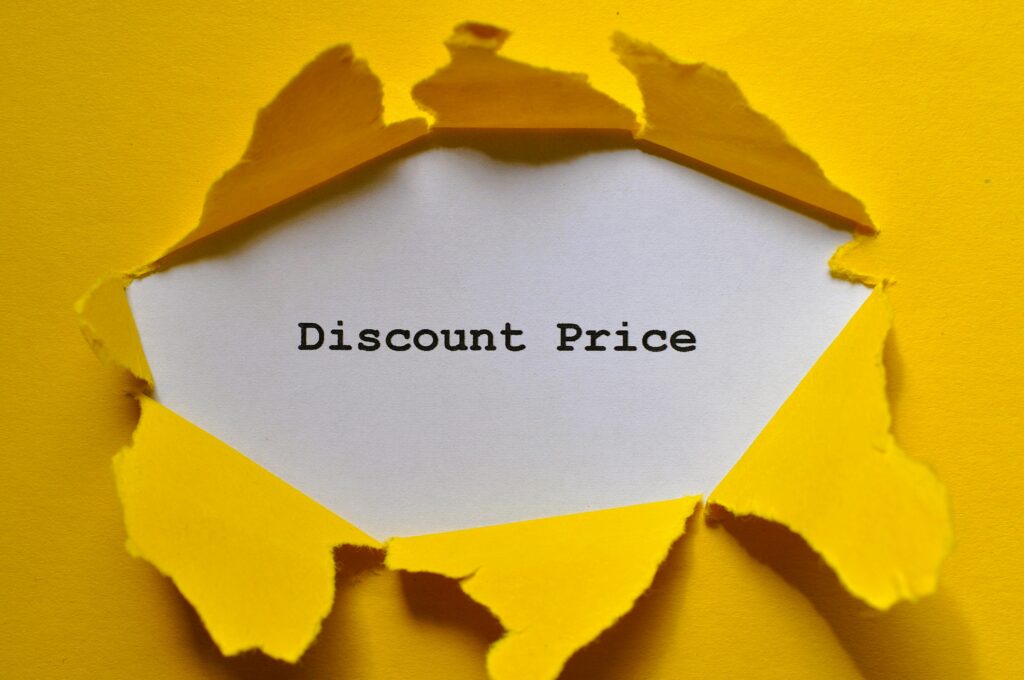 Cena w marketingu – jak wpływa na postrzeganie marki i decyzje klientów? Cena jako narzędzie marketingu – kartka z napisem discount price przebijająca żółte tło symbolizująca strategię cenową i promocje sprzedażowe