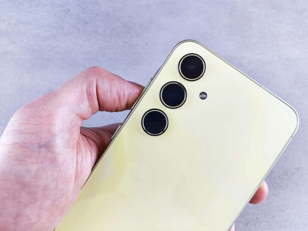 Reklama aplikacji mobilnej – jak skutecznie zwiększyć liczbę pobrań? Reklama aplikacji mobilnej – smartfon z potrójnym aparatem w dłoni jako symbol promocji aplikacji mobilnych i kampanii marketingowych w środowisku mobile