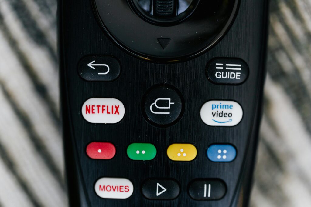 CTA (Call to Action) – jak skutecznie zachęcić użytkownika do działania? Wezwanie do działania – pilot telewizora z przyciskami Netflix i Prime Video symbolizujący szybkie kliknięcie i reakcję użytkownika.