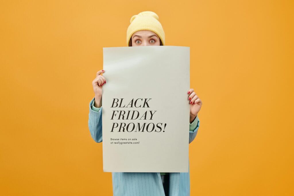 Formy promocji online – najskuteczniejsze metody zwiększania widoczności marki Formy promocji – kobieta trzymająca plakat Black Friday symbolizujący promocje sprzedażowe, rabaty i kampanie reklamowe w handlu