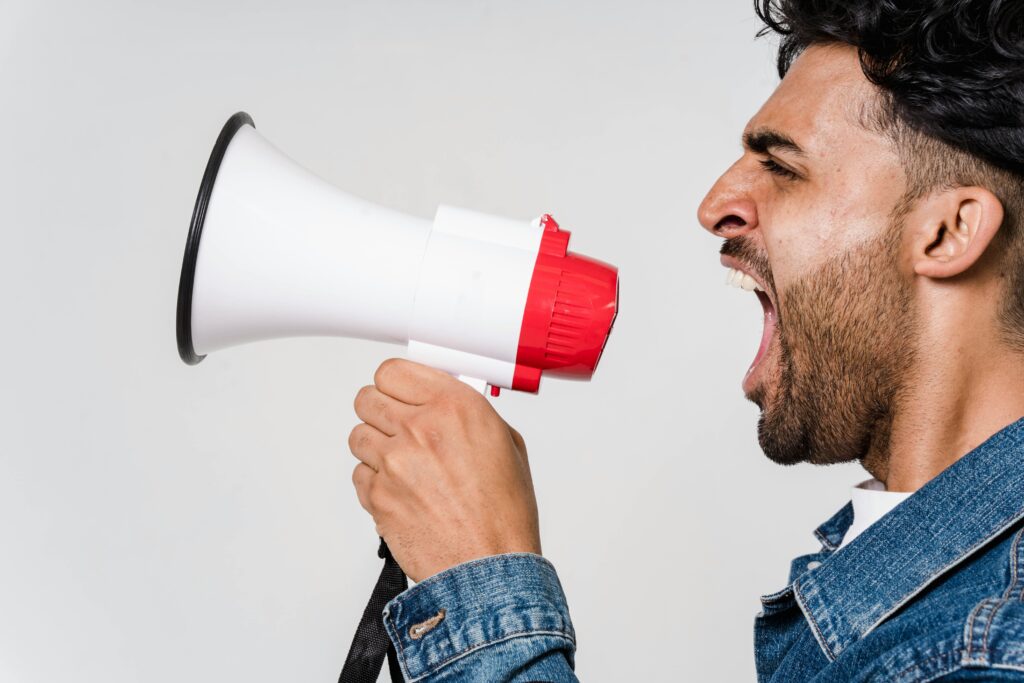 Marketing treści (content marketing) – jak budować widoczność i zaufanie marki? Marketing treści – mężczyzna mówi przez megafon jako symbol tworzenia i dystrybucji angażujących treści marketingowych.