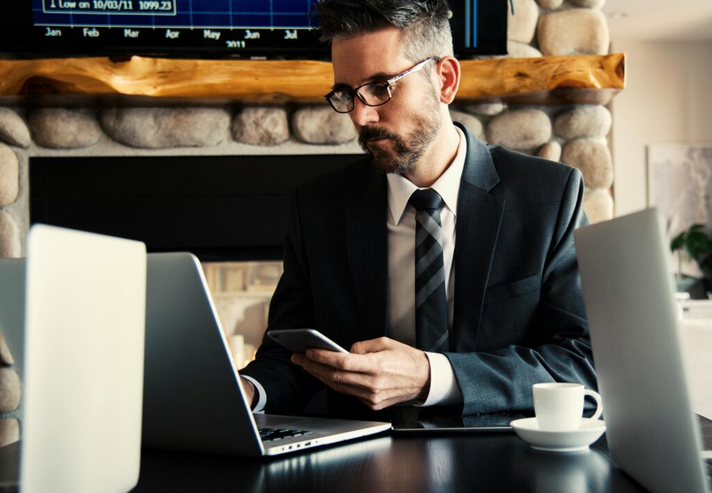 Skuteczne teksty reklamowe – jak pisać, żeby sprzedawać? Teksty reklamowe – marketer pracujący przy laptopie i smartfonie nad tworzeniem skutecznych treści promocyjnych online