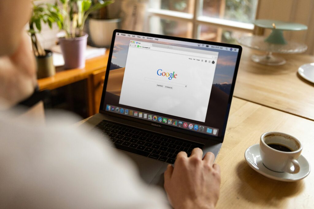 Osoba korzystająca z wyszukiwarki Google na laptopie przy biurku – zarządzanie wizytówką Google w celu poprawy widoczności lokalnej firmy, aktualizacji danych i pozyskiwania klientów online.