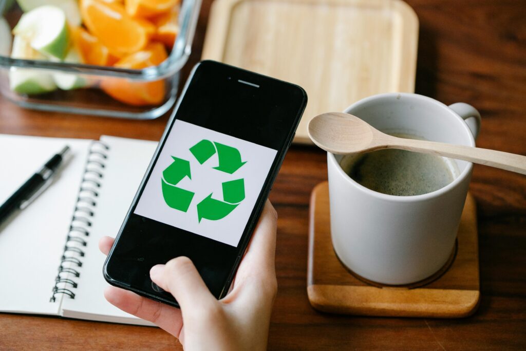 Smartfon z symbolem recyklingu na ekranie – eko marketing, czyli strategia promowania produktów i usług w oparciu o działania proekologiczne oraz komunikowanie wartości związanych z ochroną środowiska i zrównoważonym rozwojem.