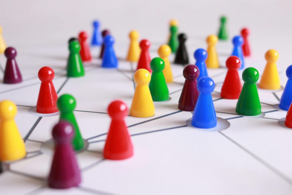 Strategia marketingowa online – jak stworzyć skuteczny plan krok po kroku? Jak napisać strategię marketingową – kolorowe pionki połączone liniami symbolizujące planowanie działań marketingowych i segmentację klientów.